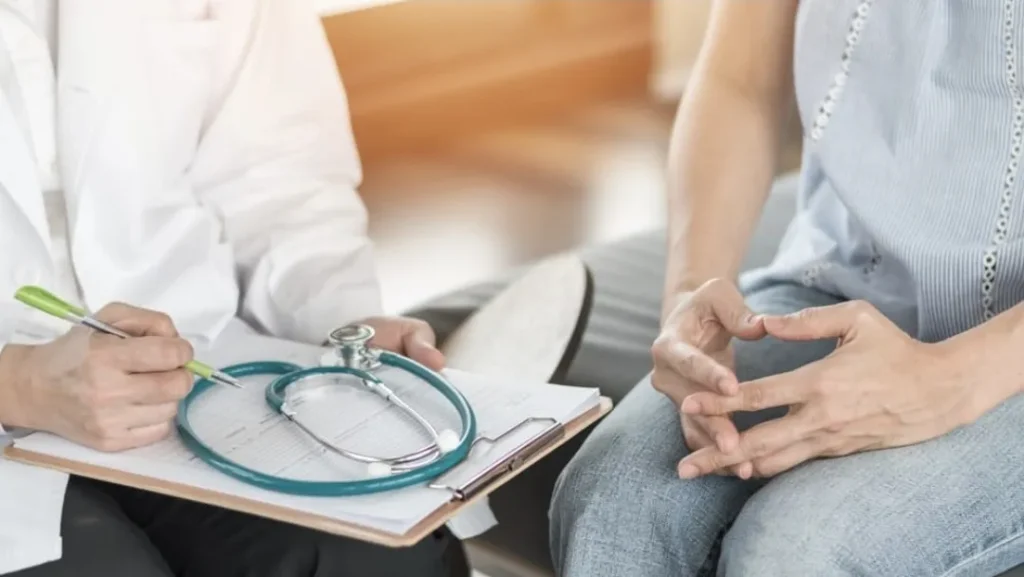 Doctor consulting with patient, writing notes on clipboard with stethoscope, illustrating pain management discussion at Cleveland Pain Relief Center.